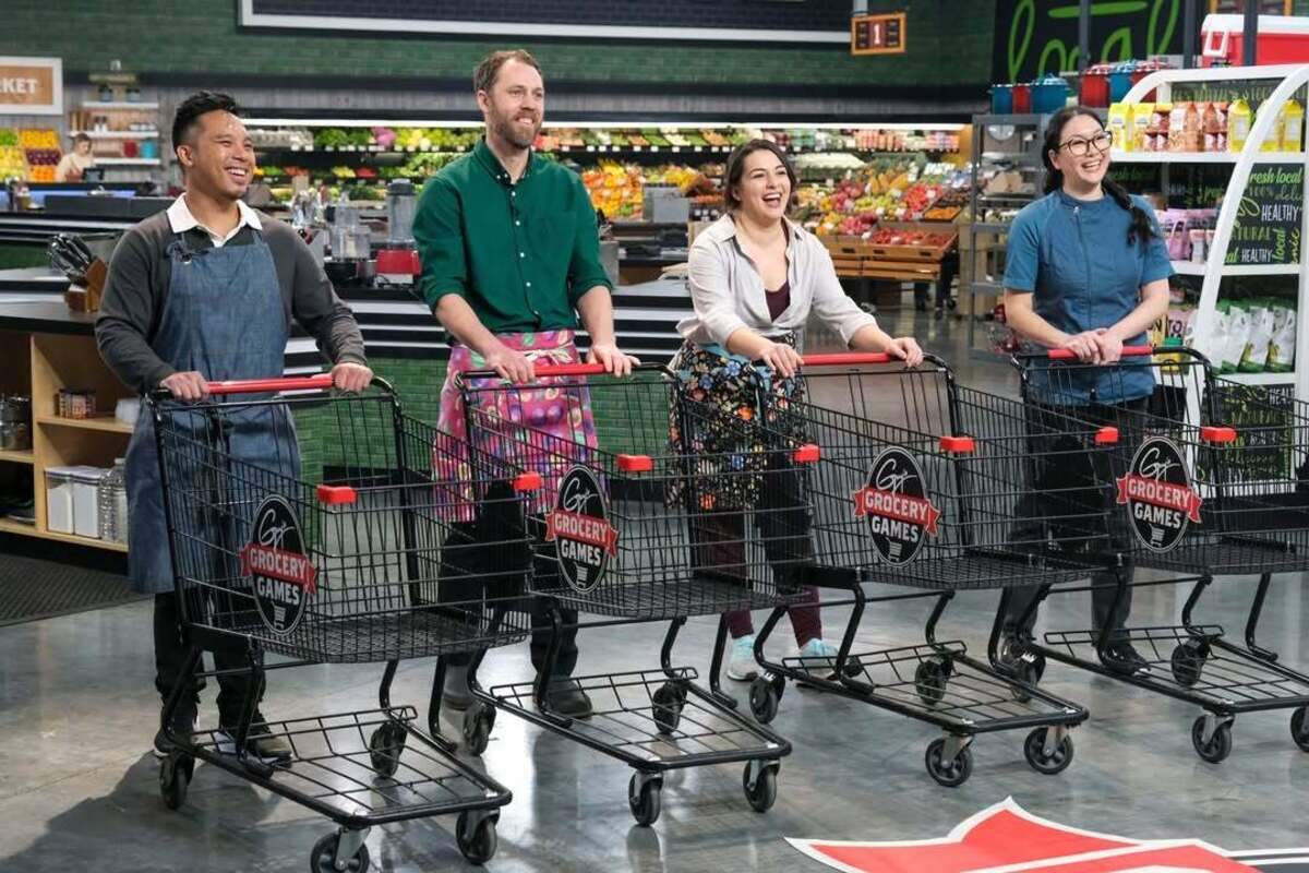 Contestants including Alex Cardoza, second from left, stand ready at their carts while listening to the game rules on “Guy’s Grocery Games.”