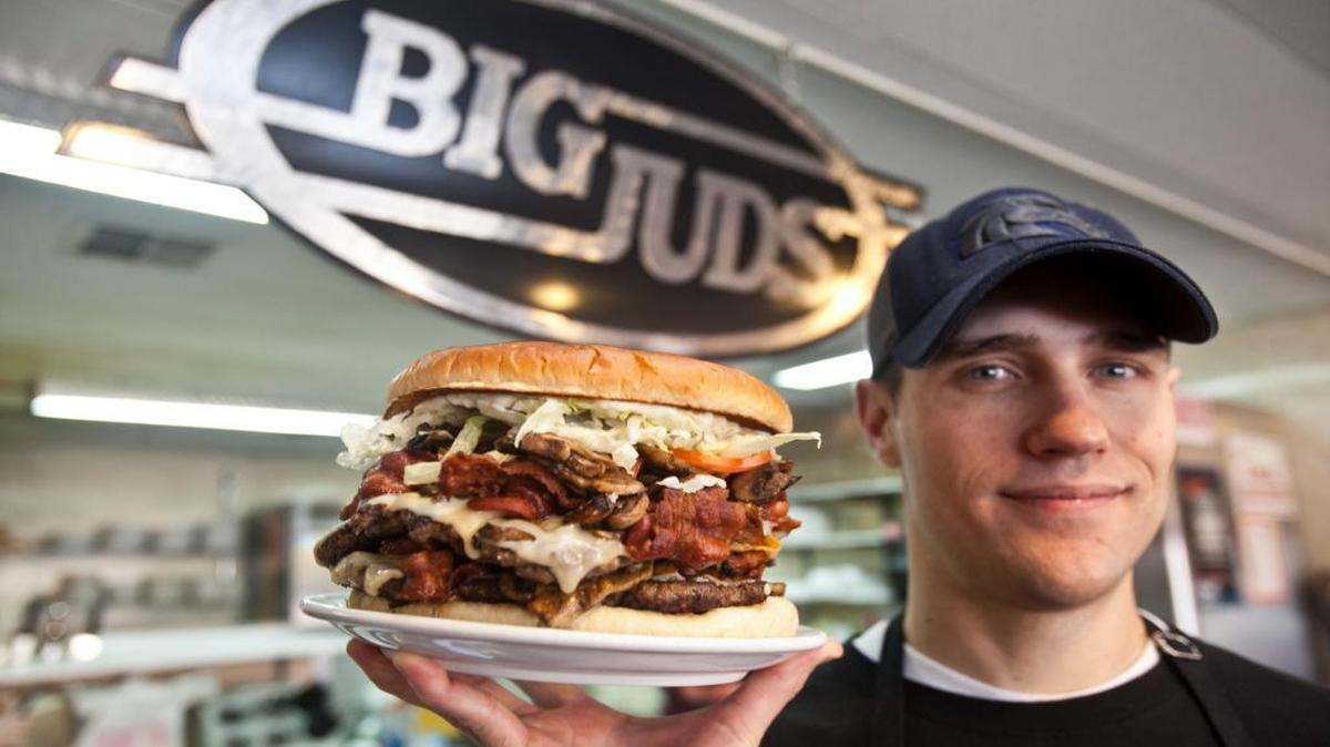 Hungry? Big Jud’s owner Chris Niederer holds the daunting Man Versus Food Burger.