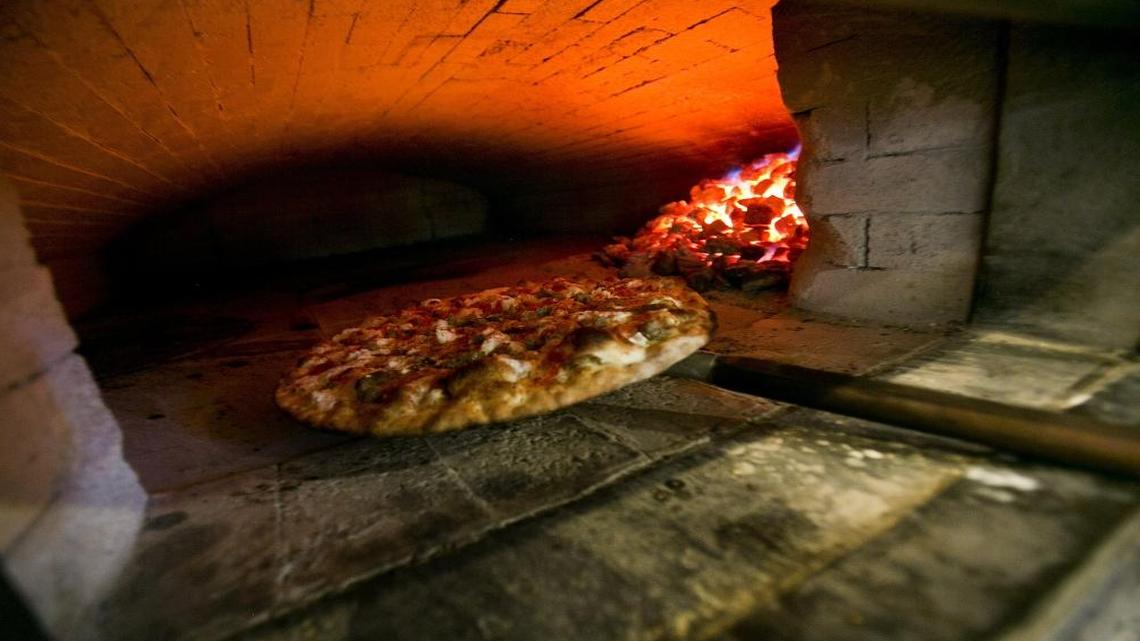 Pizzas are baked in a coal-fired brick oven.