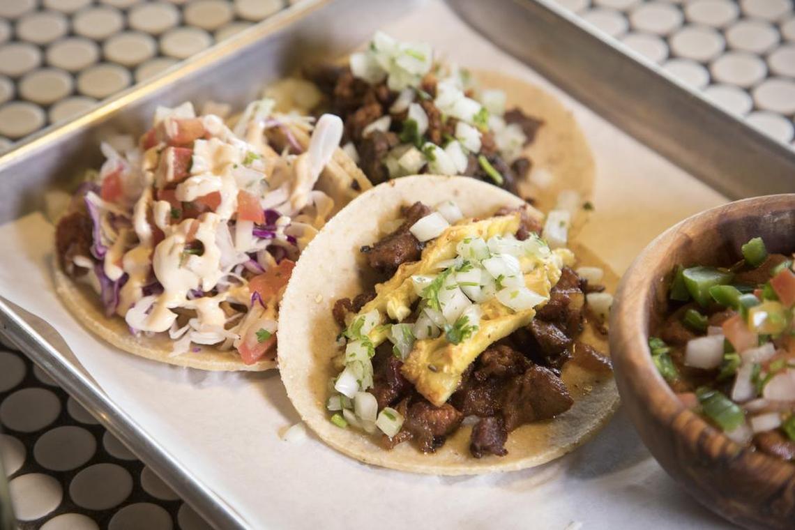 At Calle 75, the al pastor del trompo tacos, center, feature achiote marinated pork, roasted on a spindle in layers with local bacon, onion, cilantro, lime and pineapple. Also check out the Baja taco, left, or steak and swine taco. Plus a side of charro beans.