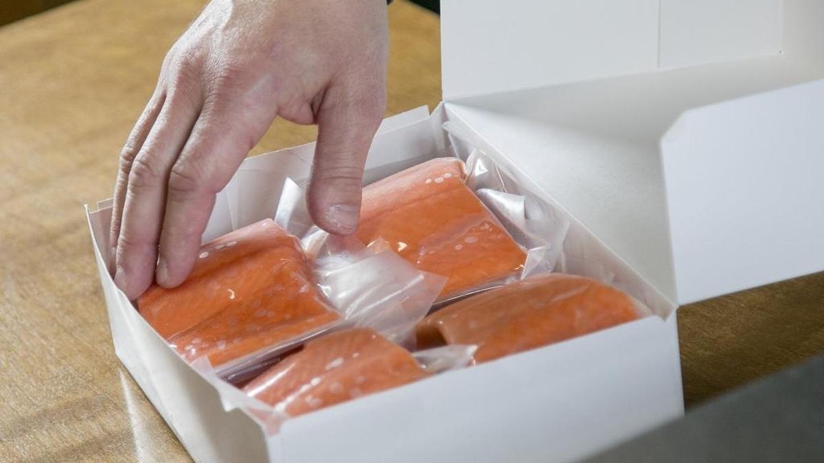 Louie Holst packs up a box of salmon filet portions for a customer.