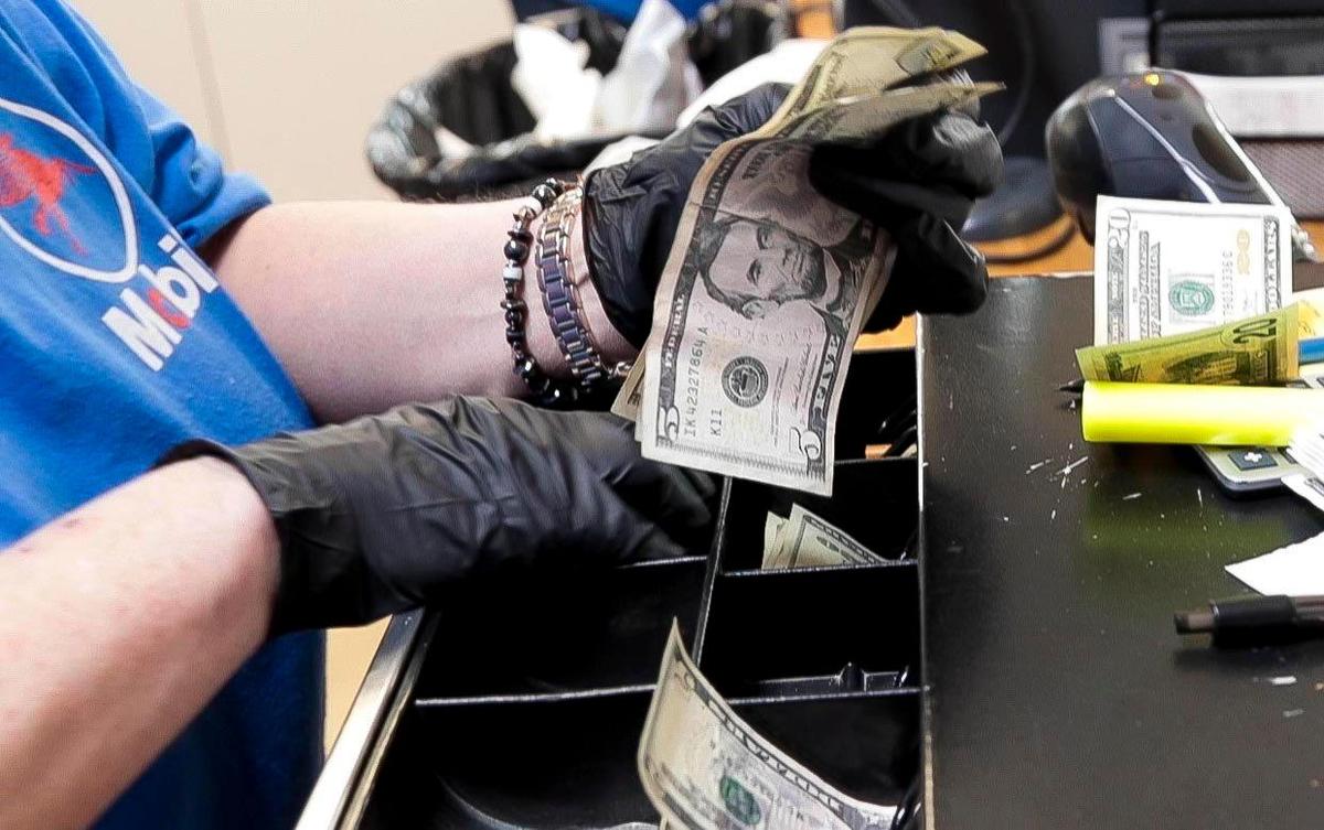 Increasingly, clerks at grocery stores and convenience stores have turned to gloves to protect themselves from surfaces that customers touch during the coronavirus crisis. This clerk makes change for a customer at the On the Fly convenience store at State Street and Collister Drive in Boise.