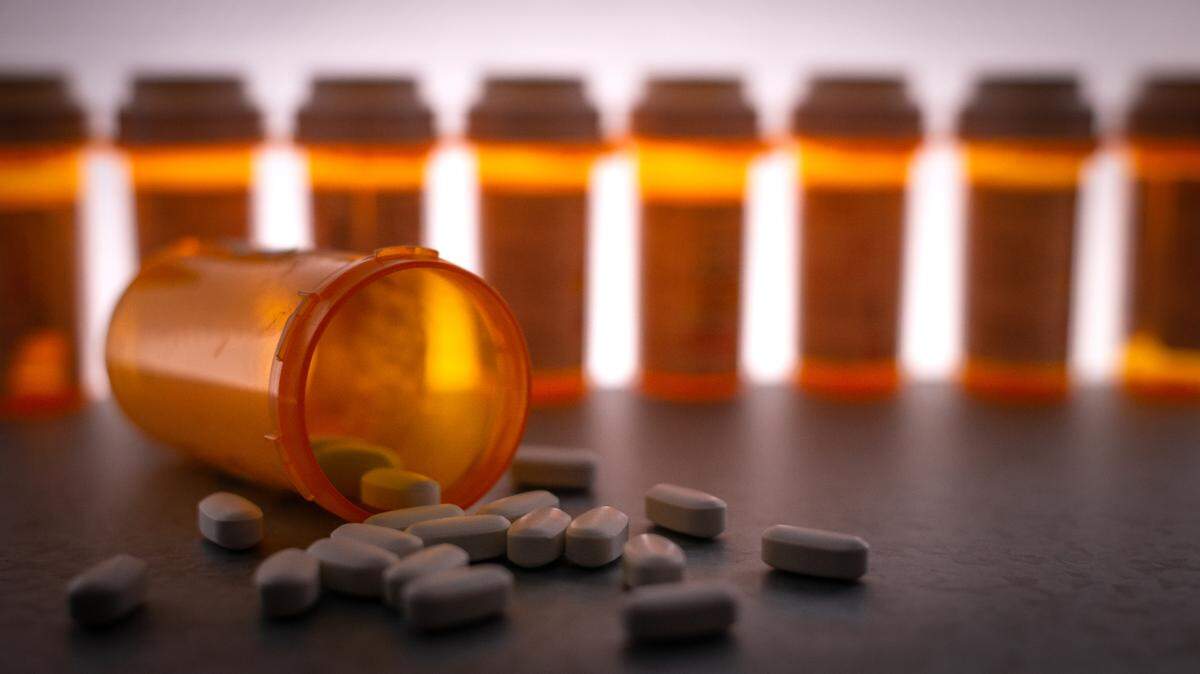 Prescription medication is strewn about, with pill bottles in the deep background.