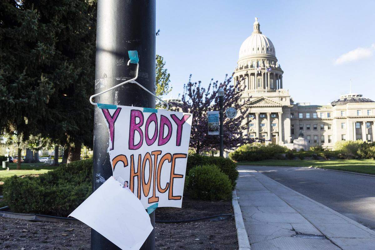 A sign reading “My body my choice” is taped to a hanger taped to a streetlight in front of the Idaho State Capitol Building in May 2022.
