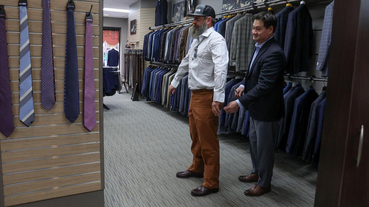 Kevin Hadway, a sales representative at Alexander Davis Men’s Clothing in downtown Boise, measures the fit of a pair of pants for customer Nate Isaak.