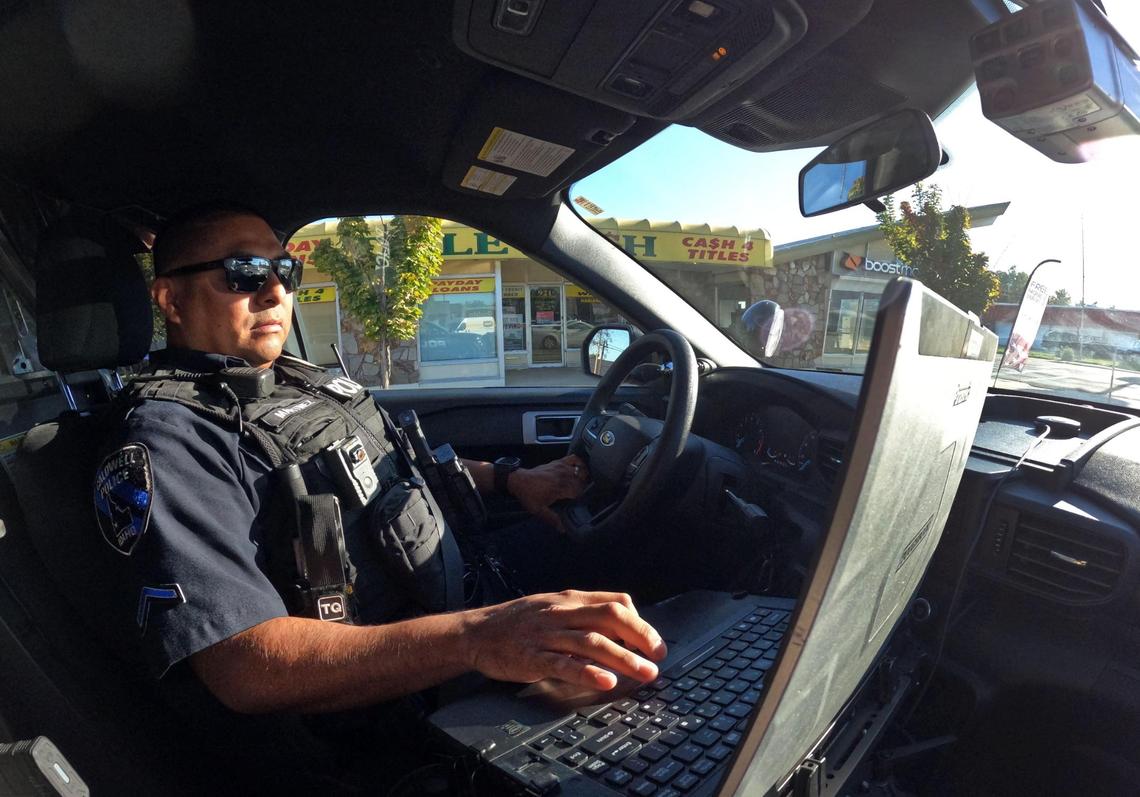Detective Martinez sits in his patrol car with one hand on his computer on Oct. 13, 2022. 