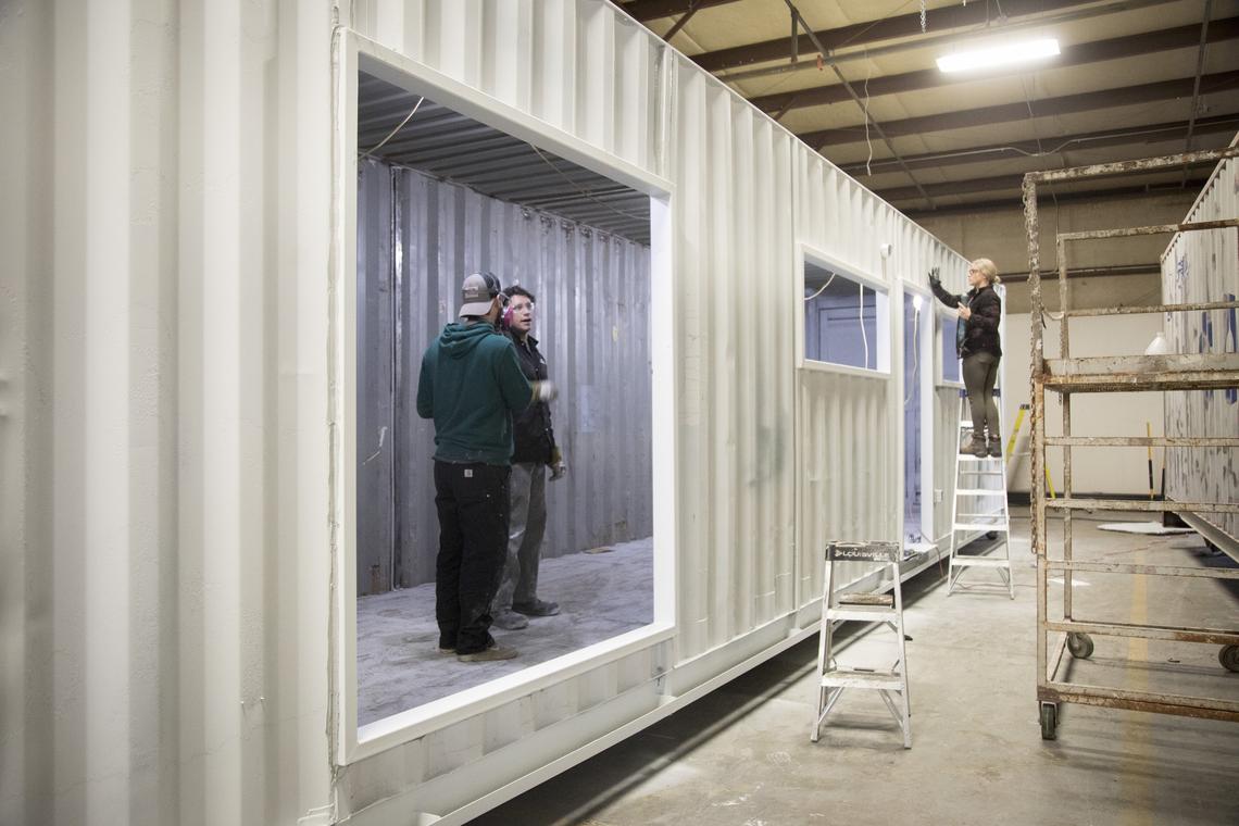 Autumn Munson, center, caulks the exterior frames in the third stage of the IndieDwell production line, from a photo from 2019. Stages one and two include cutting the openings for windows and doors and installing steel frames around them.