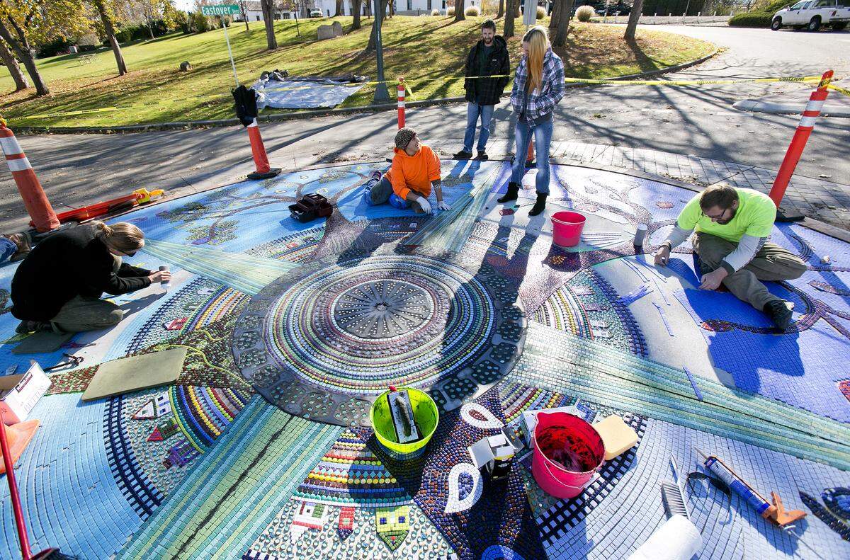 Anna Webb, Reham Aarti, and Chris Bergevin (left to right, all seated) work on a public art mosaic called "Depot Circle" on Crescent Rim Dive near the Boise Depot in November 2013.