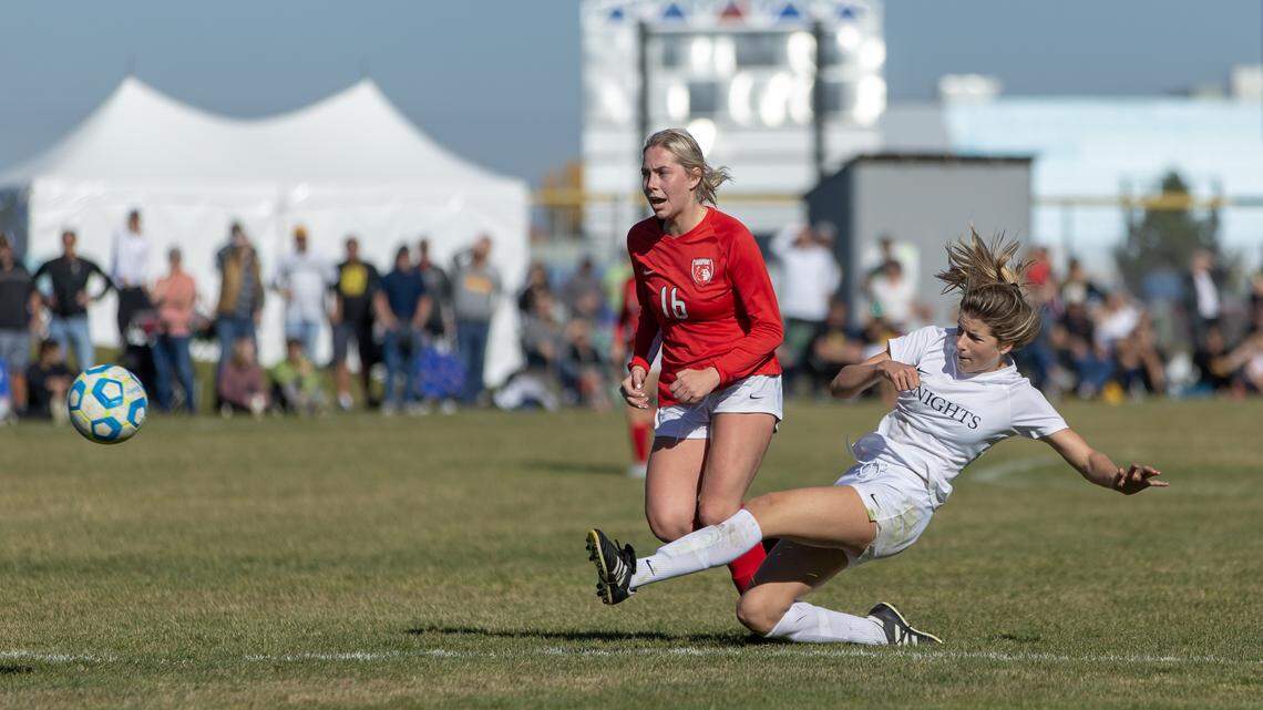Bishop Kelly senior Lauren Elwer fires a shot while Sandpoint’s Mya Darling applies pressure in the 4A girls soccer state championship game Saturday at Coeur d’Alene High.