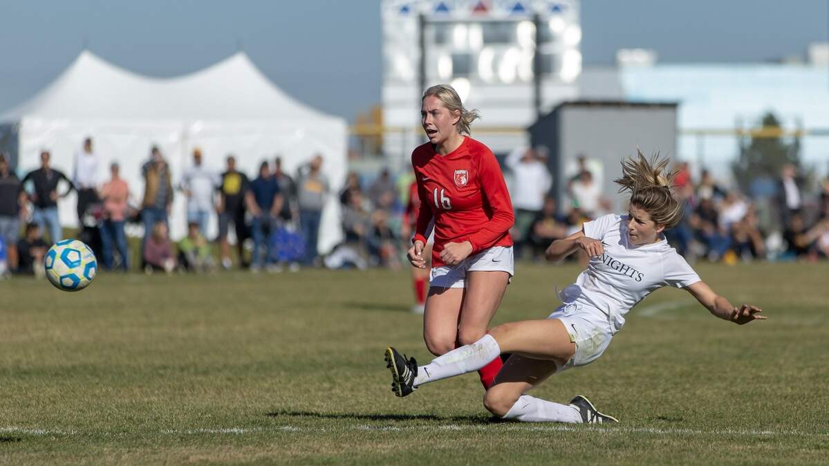 Bishop Kelly senior Lauren Elwer fires a shot while Sandpoint’s Mya Darling applies pressure in the 4A girls soccer state championship game Saturday at Coeur d’Alene High.