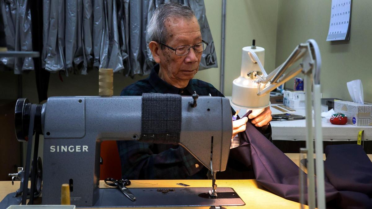 In a window display at Alexander Davis Men’s Clothing store, an old catalogue advertisement showing fall and winter styles from 1903 is paired with a modern suit and tie combination.