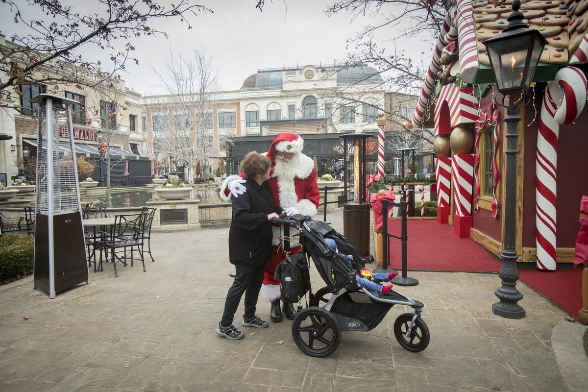 Joanne Bell, from Coeur d’Alene, gets an unexpected hug from Santa at The Village. Bell and her grandson, Aiden Bell, 13 months, were roaming around the square taking in the water show. “He loved it,” says Bell. While Bell wasn’t shopping at the moment, she’ll be back. “Oh, definitely. But not with him in tow,” she said.