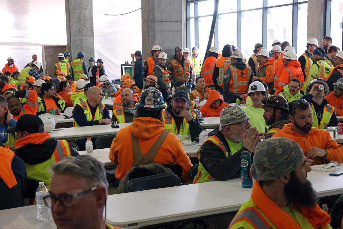 Laborers working on the Arthur relax during an event to celebrate finishing vertical construction on the building on Feb. 5.