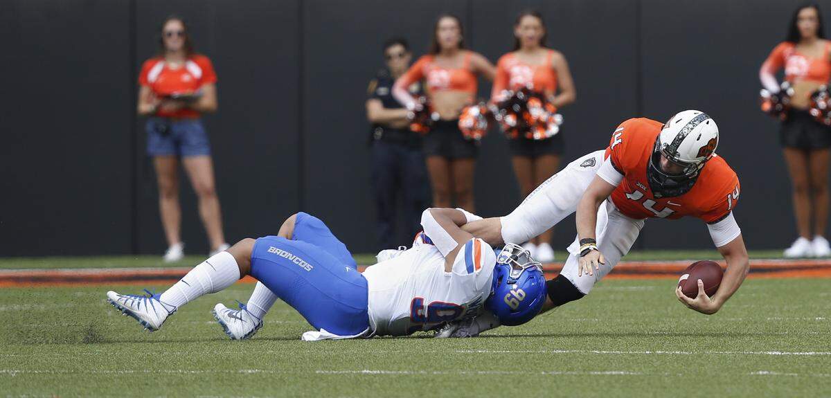 Oklahoma State quarterback Taylor Cornelius (14) is tackled by Boise State linebacker Curtis Weaver (99) in Stillwater, Okla., Saturday, Sept. 15, 2018.
