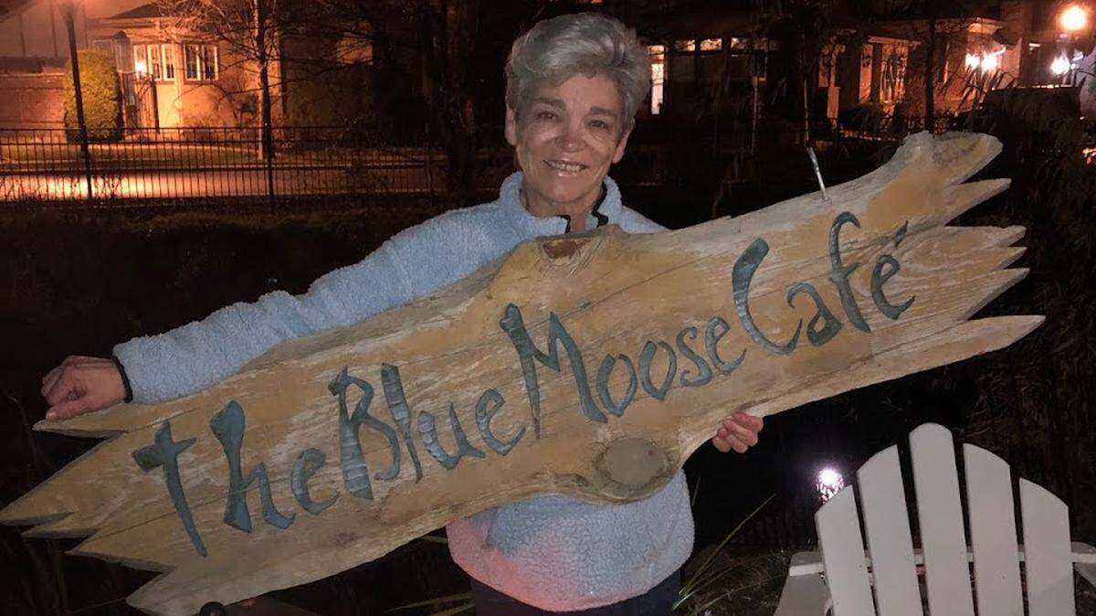Blue Moose Cafe owner Marcy Anderson poses for a photo with the Eagle restaurant’s iconic sign Tuesday night. The sign had been missing for more than four years.