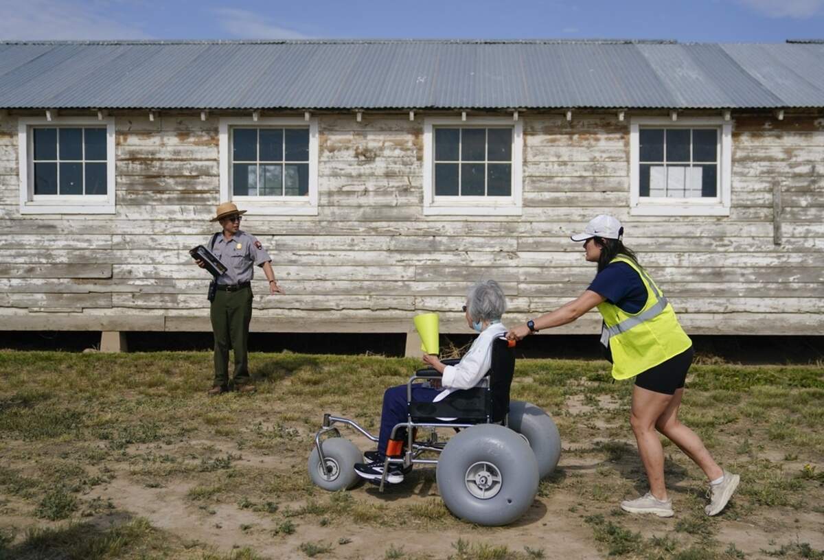 Kurt Ikeda, director of interpretation and education at Minidoka National Historic Site, brings his small Minidoka Pilgrimage tour, including Mabel Tomita, center, and volunteer Tessa Fujisaki, right, to an original barracks in July.