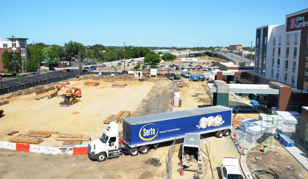 Gardner Co., developers of the Pioneer Crossing project, began work recently on a five-story office building that will go up in front of the Hilton Garden Inn, right, which is scheduled to open this summer.
