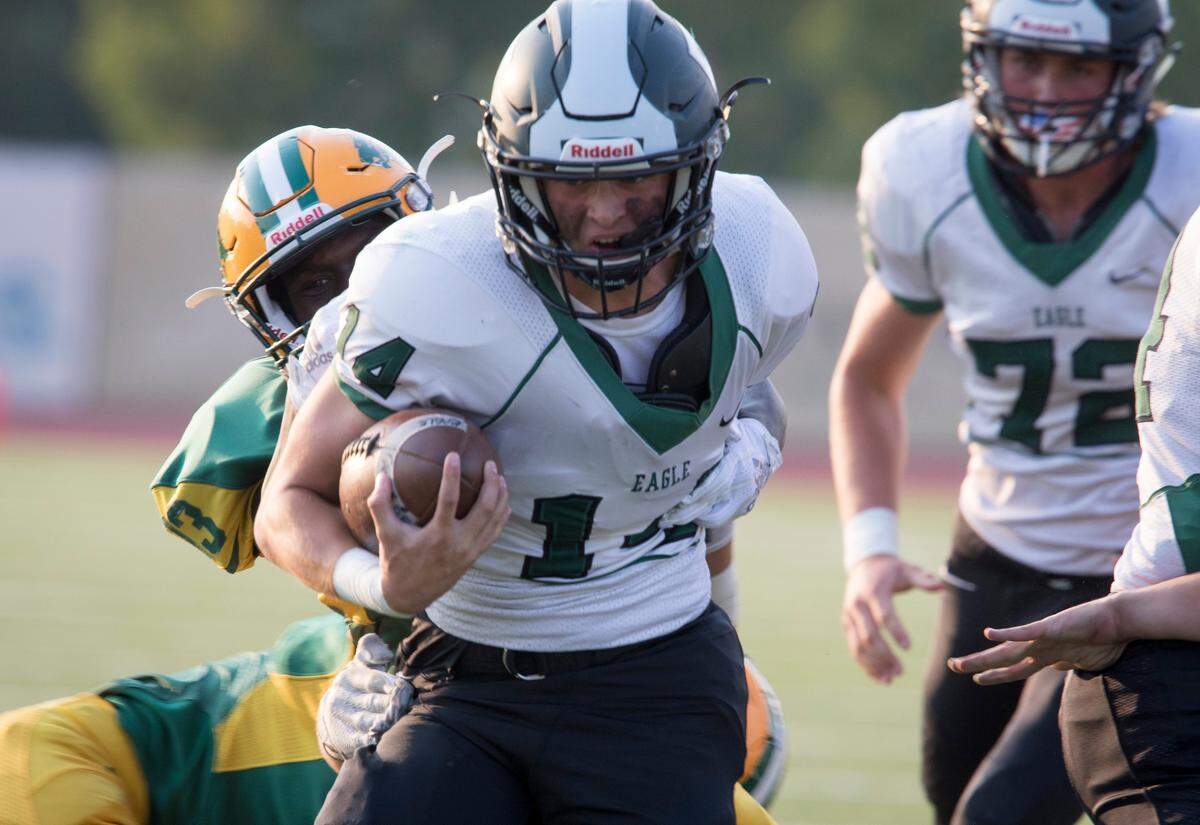 Eagle quarterback Ben Ford tries to plow through a tackle against the Borah defense on Aug. 30 at Dona Larsen Park.