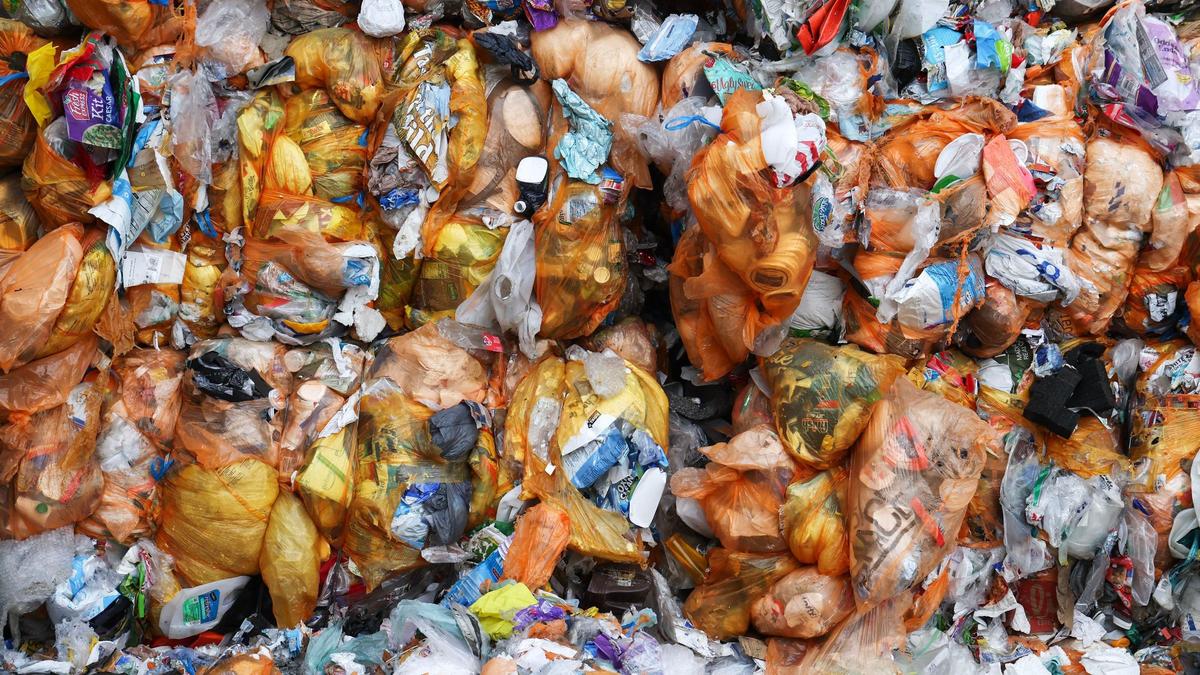 Bales of orange bags filled with plastics labeled with numbers 4-7 await shipment to be processed. 