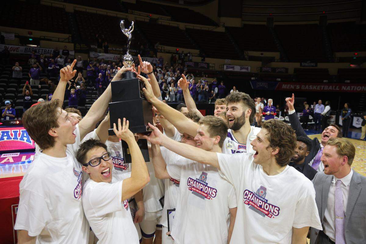 The College of Idaho men’s basketball team celebrates with the NAIA national championship trophy Tuesday in Kansas City. The Yotes beat Oklahoma Wesleyan for their second title in three years.