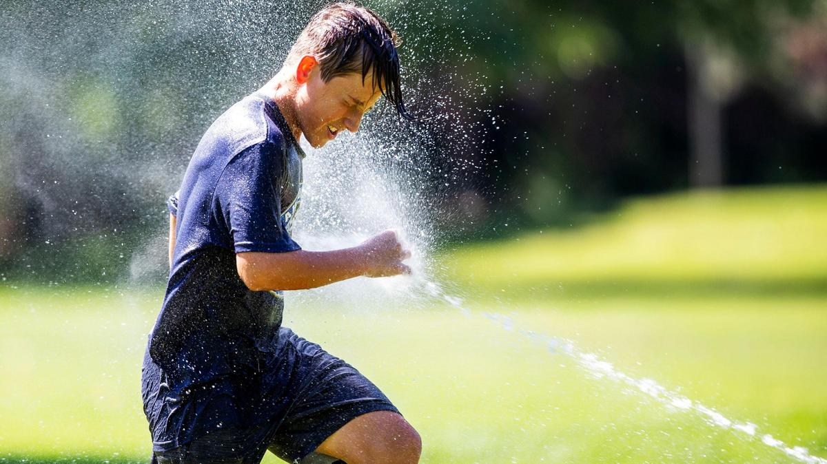 Connor Moses celebrates his 12th birthday with a cool blast of water from the sprinklers at Baggley Park in East Boise on Friday, June 16, 2021.