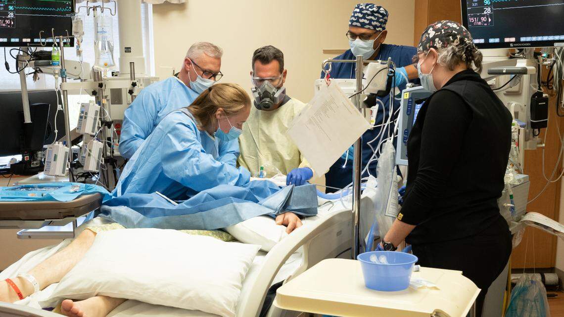 Health care workers in the ICU at Saint Alphonsus Regional Medical Center work on a patient afflicted with COVID-19. This patient had been intubated with a breathing tube for two weeks, but continued to deteriorate. They have removed the endotracheal tube and are opening the trachea to insert a more permanent tube, a procedure called tracheostomy.