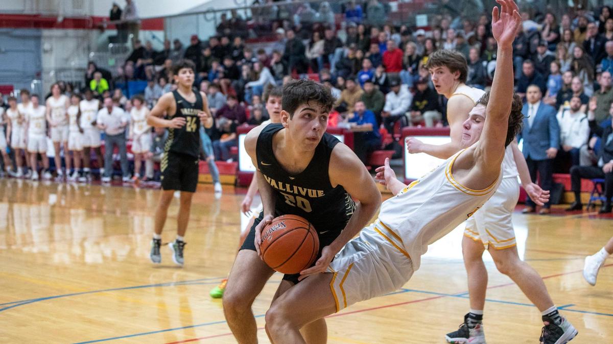 Bishop Kelly senior Blake Hawthorne, right, takes a charge from Vallivue’s Jakin Calhoun, his fifth foul, in overtime during the 4A District Three boys basketball championship game Thursday night at Nampa High.
