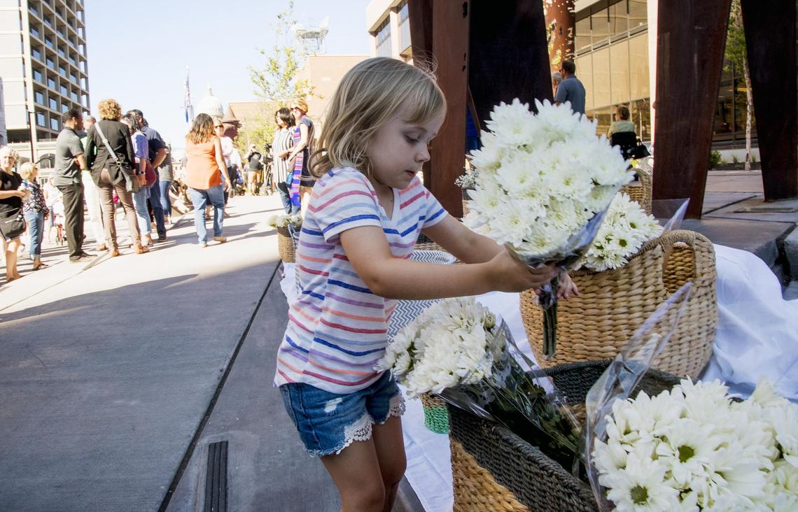 Addison Justice, 4, leaves flowers on the steps of Boise City Hall on Monday in support of the nine victims of Saturday's mass stabbing in Boise.
