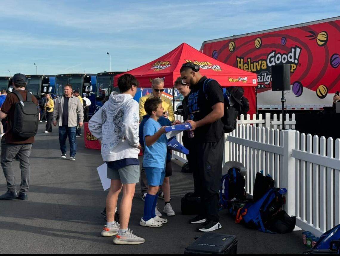 Maddux Madsen and Ahmed Hassanein sign memorabilia for fans who showed up for Boise State football’s arrival in Arizona for the Fiesta Bowl.