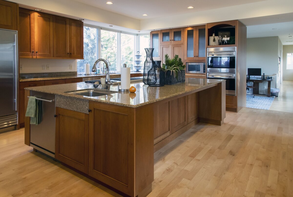 A plumbed island centers the kitchen space that is equipped with stainless steel appliances and a natural wood decor.