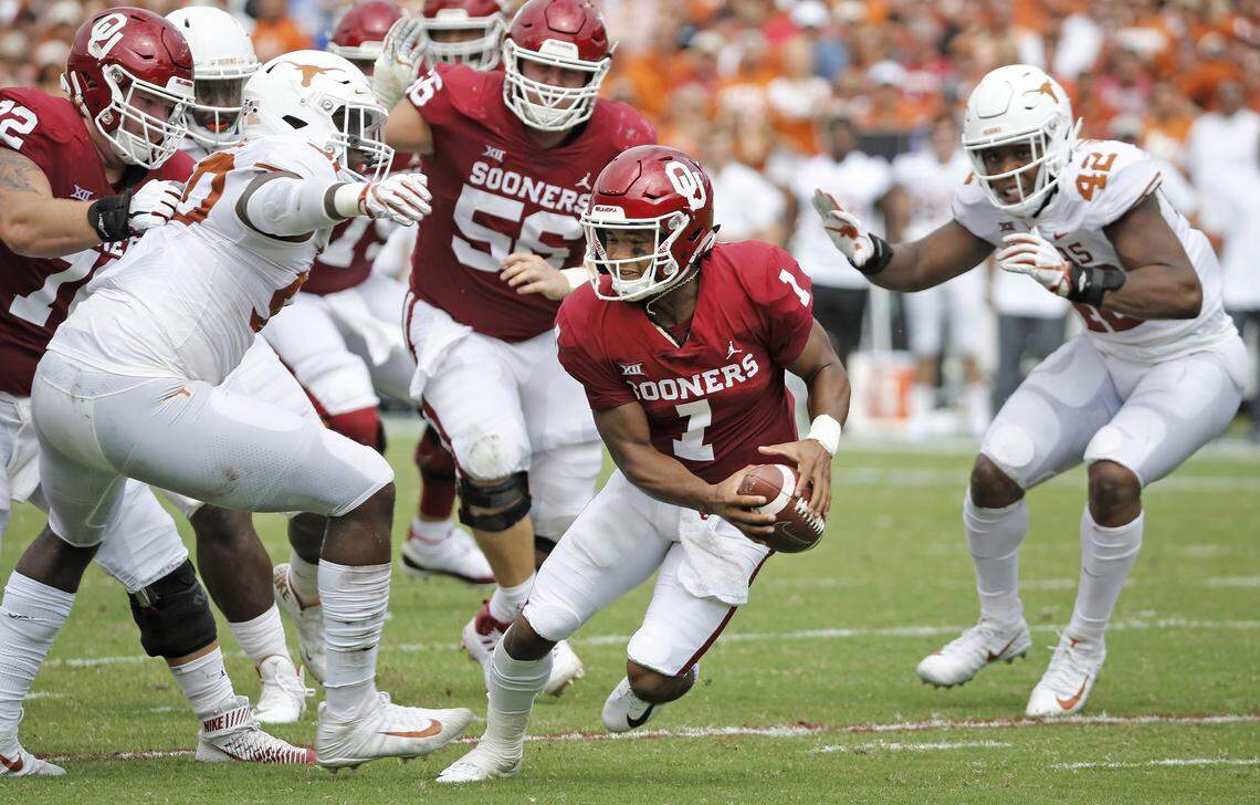 Oklahoma quarterback Kyler Murray (1) looks for room to run as he is pressured by Texas defenders Marqez Bimage (42) and Charles Omenihu (90) in the first half at the Cotton Bowl in Dallas on Saturday, Oct. 6, 2018. (Louis DeLuca/Dallas Morning News/TNS)