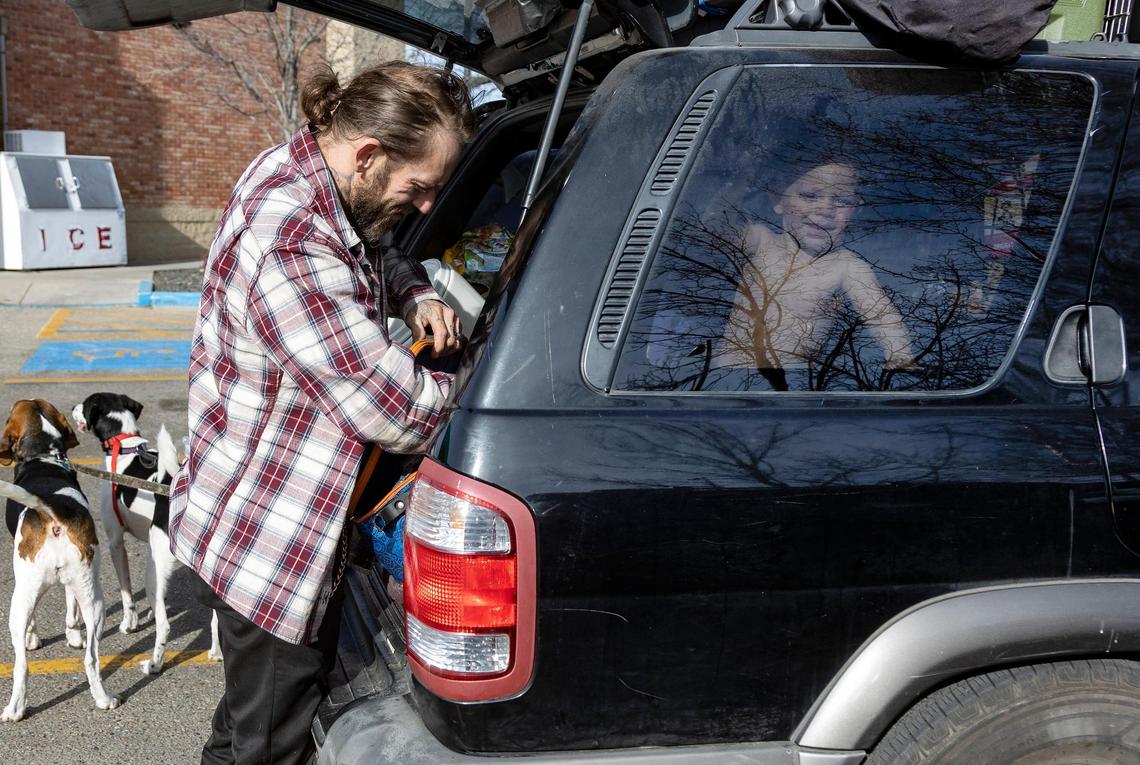 Thomas Lowder lets the dogs out of the car so he can pull out a set of clothes for Elijah, 1, who smiles out the back window while the family is parked in Boise in early February.