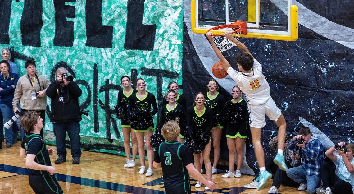 Meridian’s T.J. Sanor hangs from the rim after a dunk against Mountain View last season.