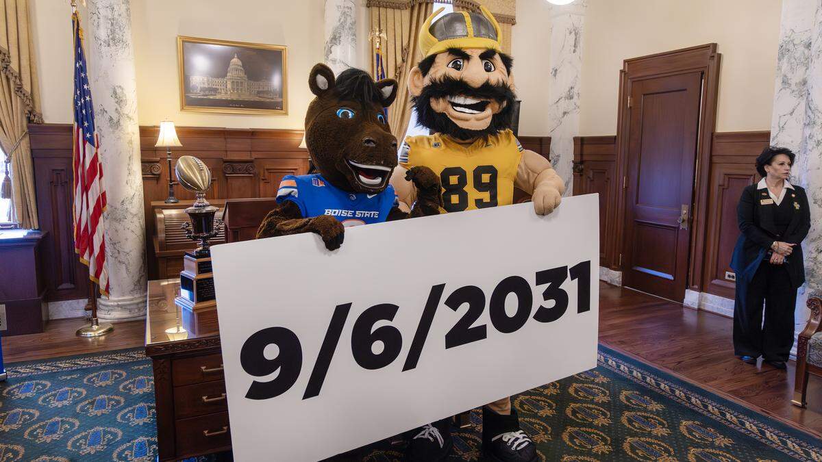 Boise State University mascot Buster Bronco and University of Idaho mascot Joe Vandal hold a sign announcing the date of a football game the former rivals will play.
