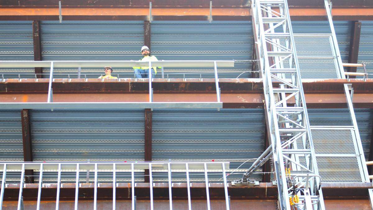 Two construction workers peer down from a floor on the south tower.