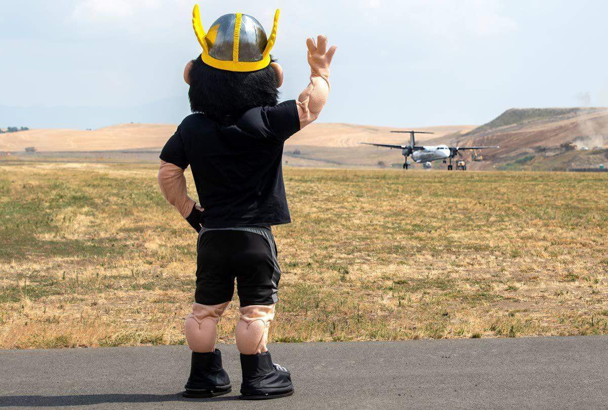 University of Idaho mascot Joe Vandal, on the runway at the Pullman-Moscow Regional Airport, waves goodbye to the inaugural Alaska Airlines Flight 2496 to Boise.