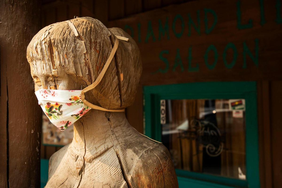A woodcarved statue in front of Diamond Lil’s Steakhouse and Saloon in historic Idaho City is decorated with a protective face mask.