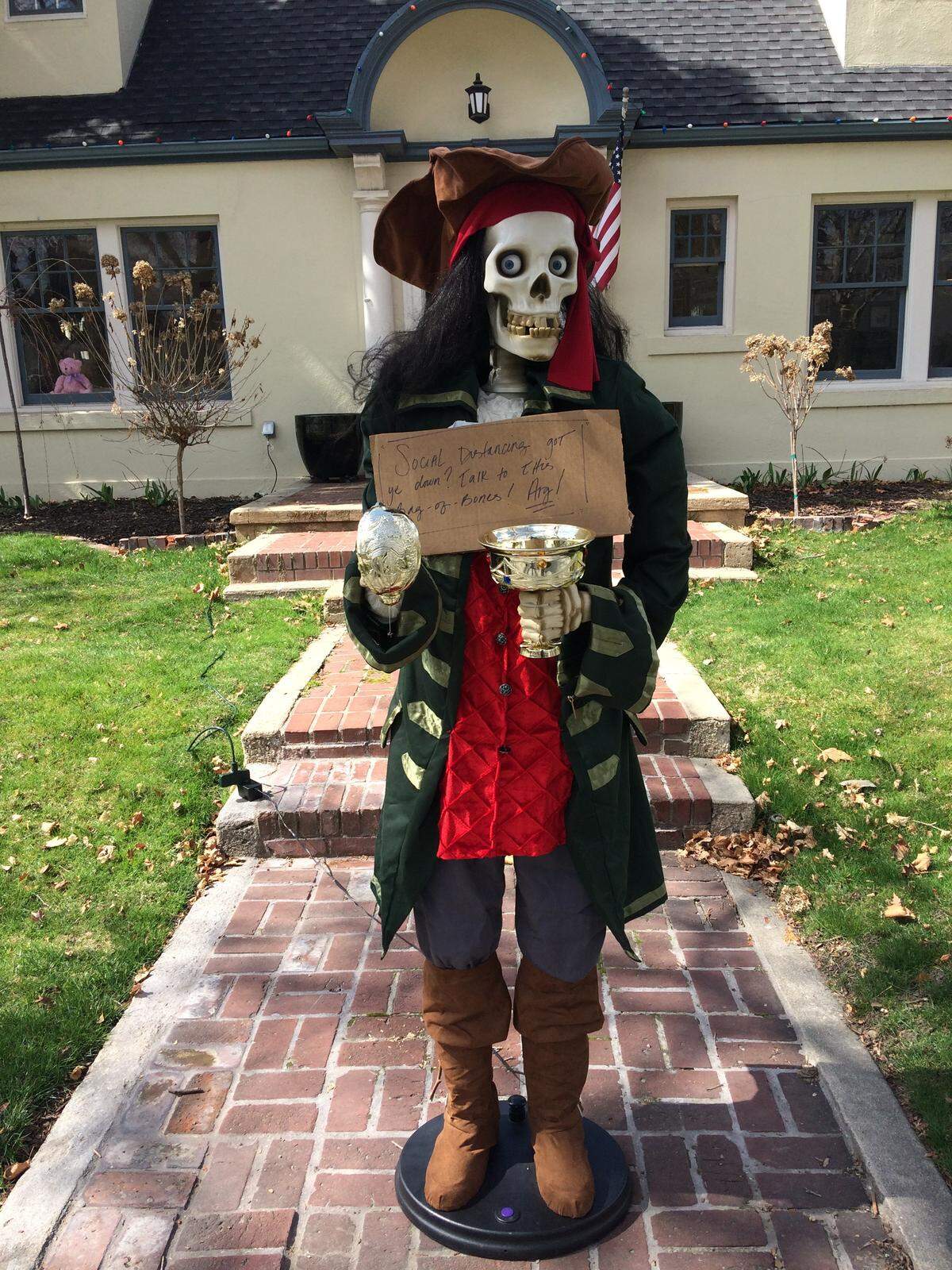 Halloween and Christmas displays are popping up as light diversions from the stay-home order. This gentleman on Harrison Boulevard holds a sign that says, “Social distancing got ye down? Talk to this Bag-of-Bones! Arg!”