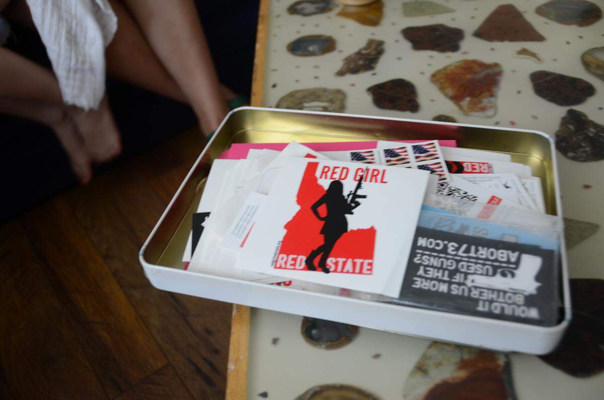 Miranda Otto keeps her “Red Girl, Red State” stickers in a tin along with stamps, envelopes and other decals. She sells them online and estimates she has mailed out about 500 so far. The original version of the sticker features a silhouette of Otto holding her daughter Rahab on one hip and a gun in her opposite hand.