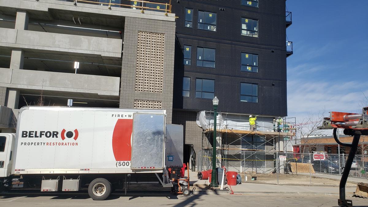 Construction workers apply texture underneath an awing at the Jules on Third apartment building on Friday. A crew from Belfor Property Restoration, which provides fire cleanup services, was also at the building.