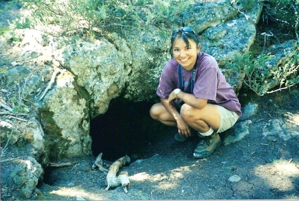 Marcie Carter, who began her career with Nez Perce Tribe’s wildlife division working on the wolf project, poses for a photo in front of a wolf den.
