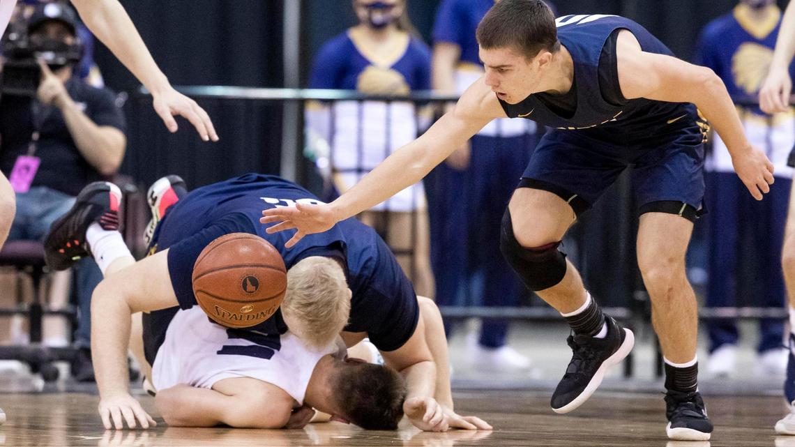 Meridian big man Brody Rowbury topples onto Lake City’s Zach Johnson as teammate Drayson Fisher grabs the loose ball in the 5A boys basketball state championship Saturday at the Ford Idaho Center in Nampa.
