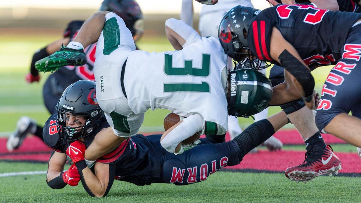 Owyhee defensive back Logan Haustveit, bottom, brings down Eagle’s Noah Burnham last season.