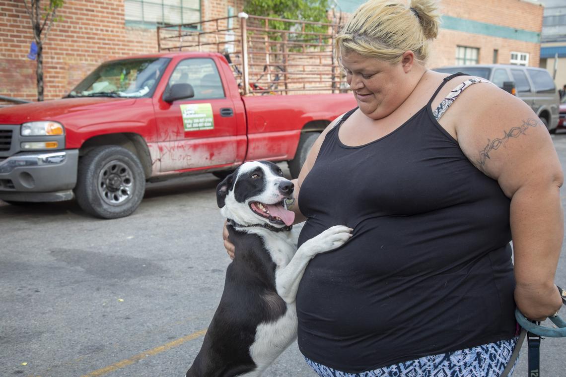 Kelly Clausen plays with Petey, her dog, outside Interfaith Sanctuary. The truck for the landscaping and lawn business that she and her fiance run is parked there overnight.