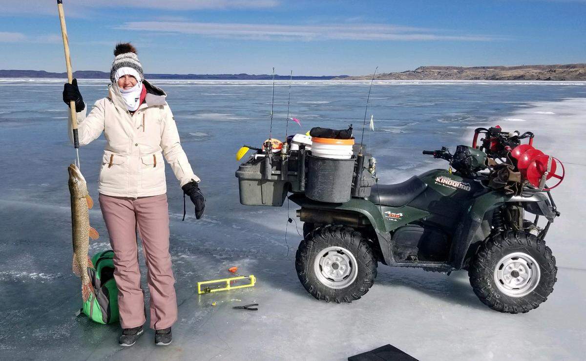 Tammy Ostermiller holds a pike she caught at Fort Peck Reservoir last week. Her husband, Jared, likes to be mobile when he ice fishes, using an ATV to motor from hole to hole.