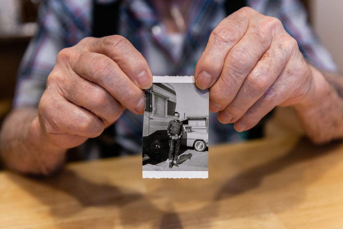 Delmar Scroughams holds an old photograph of himself posing with his guns.