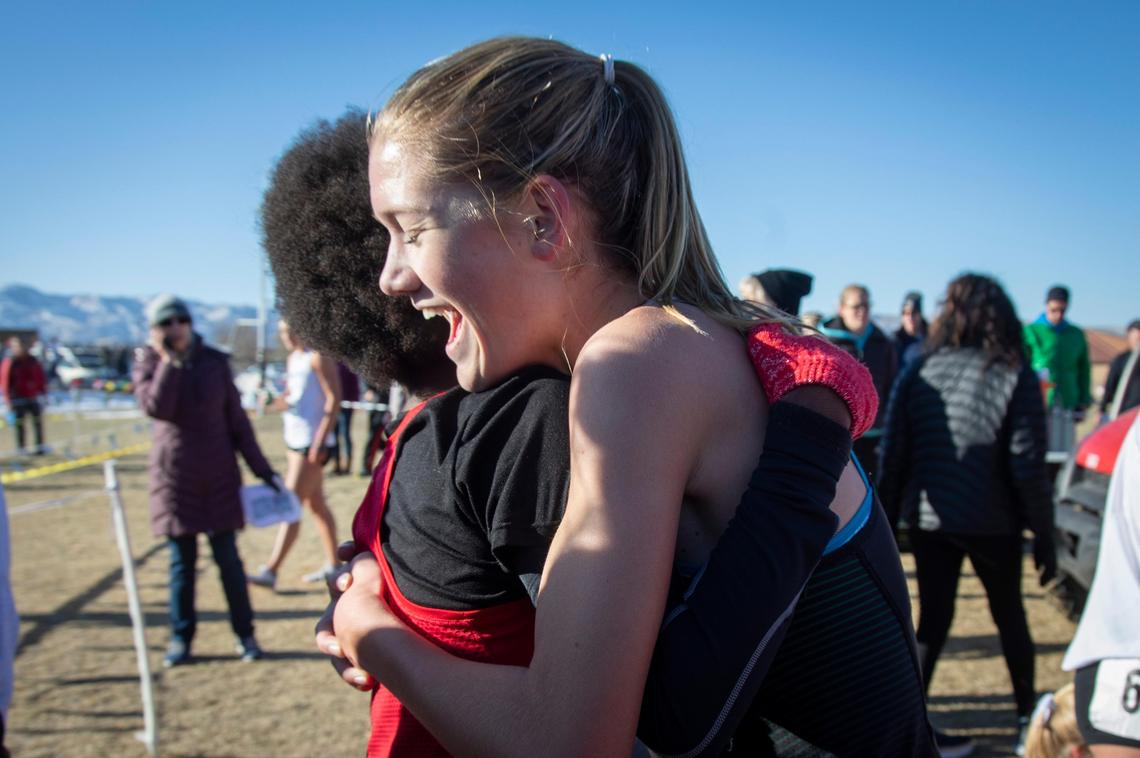 Eagle junior Lizzie Dildine gets a congratulatory hug after her surprise first-place finish in the 5A girls state cross country championship Saturday in Pocatello.