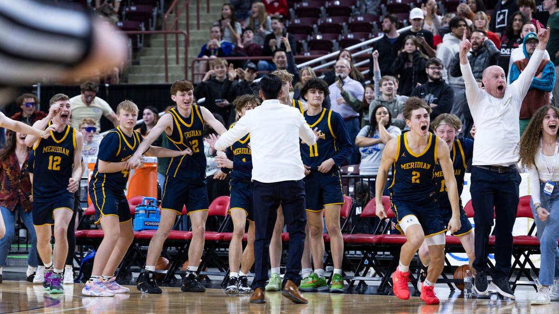 Meridian’s bench celebrates after upsetting defending champ Owyhee 51-48 in overtime in the first round of the 5A boys basketball state tournament Thursday at the Ford Idaho Arena in Nampa.