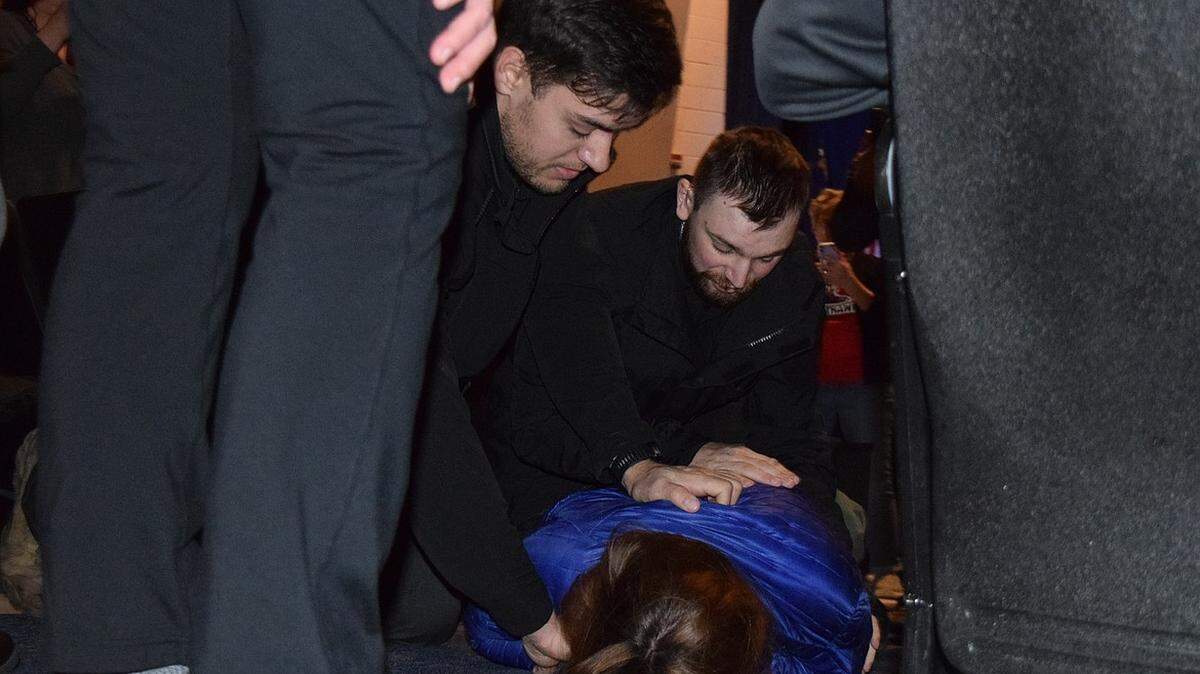 Borrenpohl is seen held against the ground by security.