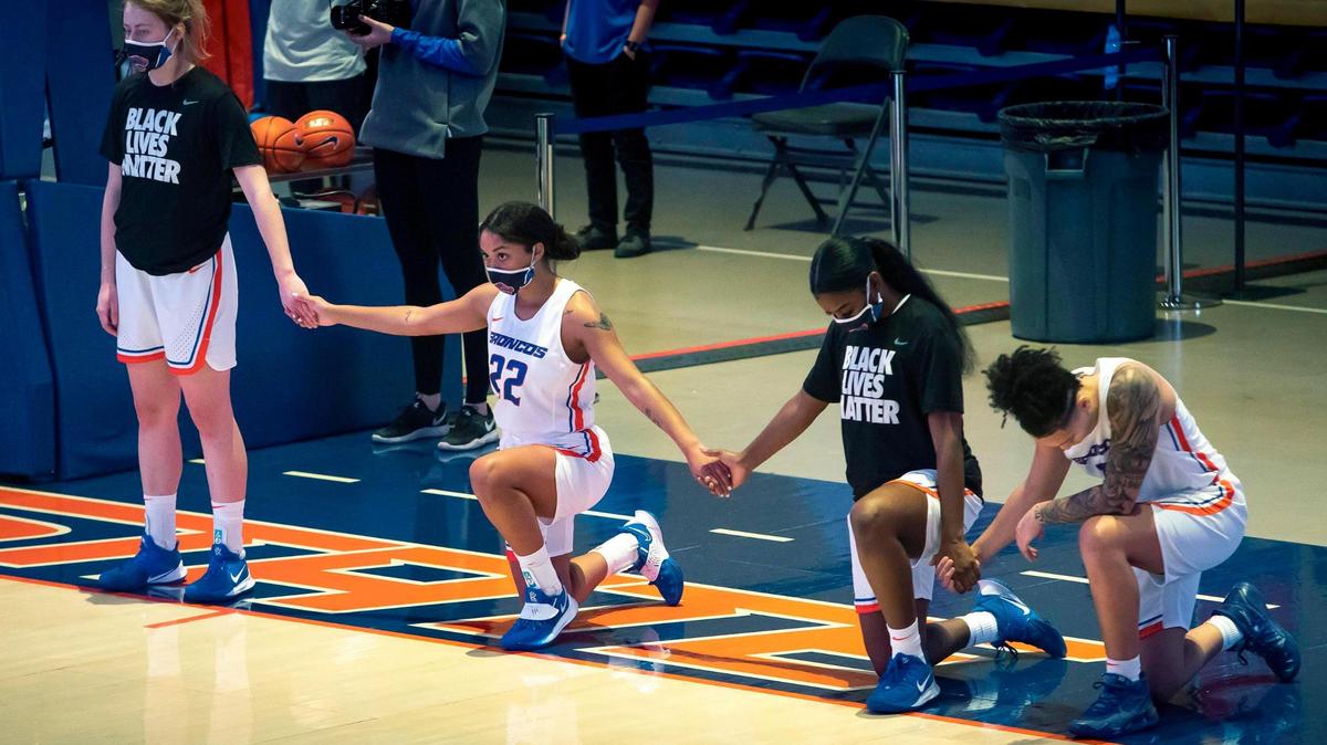 Boise State women’s basketball players Raigan Reed, second from left, Kimora Sykes and Jade Loville take a knee during the national anthem at the start of their game against San Jose State on Dec. 31 at ExtraMile Arena.